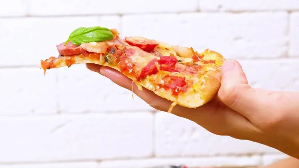 Een hand die een stuk pizza vasthoudt — Stockfoto