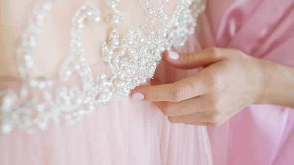 Genç bir kadının eli bir gelinliğe dokunuyor.