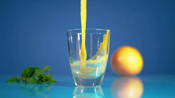 Congelar el movimiento del proceso de verter el chorro de jugo de naranja con un chapoteo —  Fotos de Stock