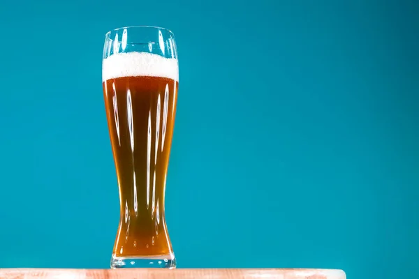 Biralar mavi arkaplandaki uzun cam kadehte fotokopi alanı ile