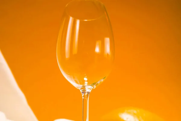 Giet rode wijn uit fles in glas op oranje achtergrond — Stockfoto