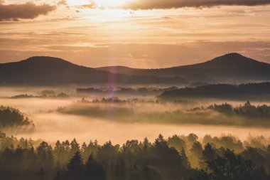 Arkasında dağ olan bir su kütlesinin üzerinde gün batımı.