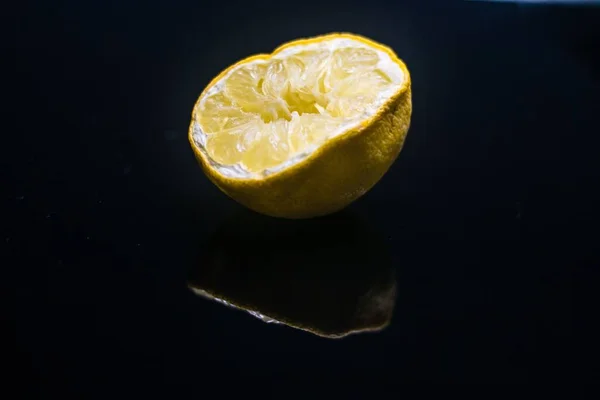 Un morceau de fruit, un demi citron sur fond noir — Photo