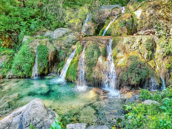 A large waterfall next to a river with Plitvice Lakes National Park in the background — Stock Photo, Image