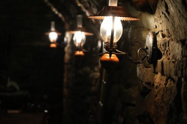 Parlayan lambaları olan eski bir taş mahzenin duvarına bak.