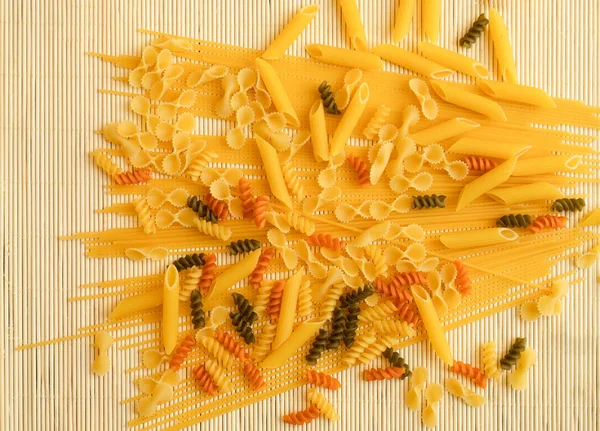 spagetti ve ahşap çizgi üzerinde farklı renkte makarna çeşitleri beyaz arka plan desenli. Soyut ve üst görünüm fotoğrafı. dağınık makarna.