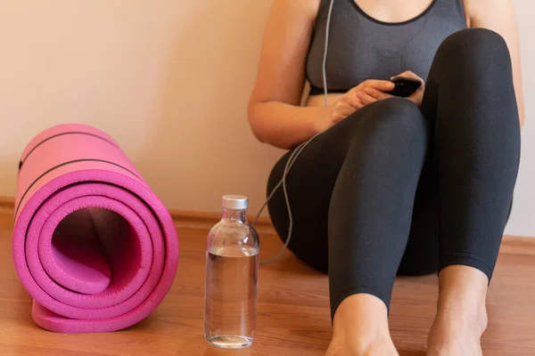 Kadın, spor pembesi su şişesinden sonra dinleniyor. İnternetteki yoga meditasyon egzersizinden sonra kulaklıkla müzik dinlemek. Karantina koronavirüsü kilitlendi. Aktif ol. sağlıklı bir hayat. Yorgun