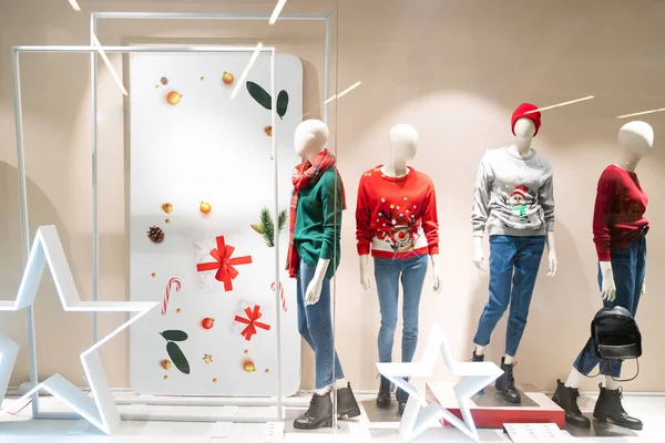 Noel ve alışveriş merkezinde yeni yıl heyecanı. Yeni yıl için markalar dekore edilmiş pencereler. Renkli ışıklar çirkin Noel kazakları, mankenler, dekorasyon, yeşil, kırmızı ve altın sarısı. boş alan