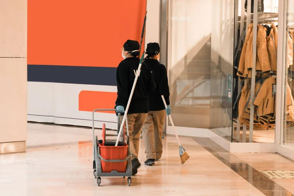 Alışveriş merkezinde çalışan maske takan kadın temizlikçiler. Coronavirus salgını temizleme ve dezenfeksiyon. yeni normal. çeşitlilik.