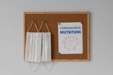 Yeni koronavirüs mutasyonu. Mutasyona uğramış koronavirüs. Mesaj at. Renkli raptiyelerde asılı cerrahi tıbbi maskeler. Coronavirus salgını 2021, illüstrasyon, hatırlatma, uyarı, kavram.