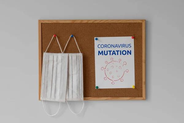 Yeni koronavirüs mutasyonu. Mutasyona uğramış koronavirüs. Mesaj at. Renkli raptiyelerde asılı cerrahi tıbbi maskeler. Coronavirus salgını 2021, illüstrasyon, hatırlatma, uyarı, kavram.