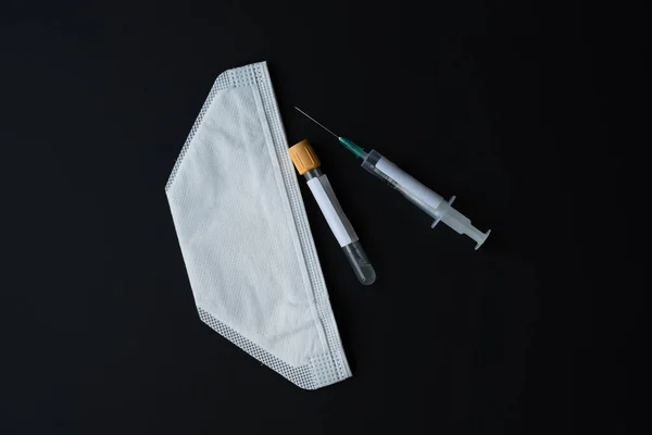 Tıp, sağlık ve salgın hastalık konsepti. Tıbbi maske, test tüpü ve şırınga aşısı siyah arka plan. mutasyon, mutasyona uğramış yeni Coronavirus SARS-CoV-2 VUI 202012-01.Covid - 2020, kopyalama uzayı.