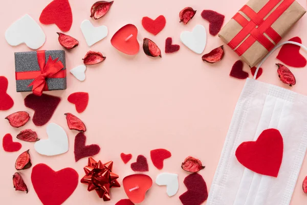 Sevgililer Günü için kompozisyon 14 Şubat Yumuşak pembe arka plan çerçeve tıbbi maske hediyeler mum güller kırmızı kalpler düz düz bir görüş alanı 2021 Love konsepti covid-19