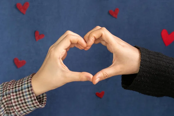 The hands of people are the heart shape. Composition for Valentine\'s Day February 14th dark blue background and red hearts 2021 Love concept. selective focus
