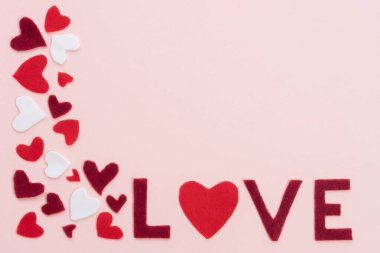 14 Şubat Sevgililer Günü için kompozisyon. Yumuşak pembe arka plan keçeden kesilmiş kırmızı kalpler ve aşk sözcükleri. Tebrik kartı. Düz görünüm fotokopi alanı 2021 Sevgi dolu konsept çerçeve.