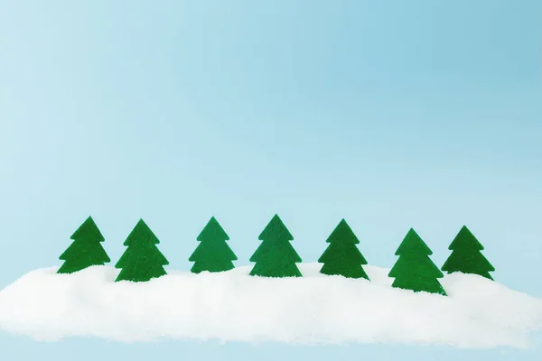 Grüne Weihnachtsbäume auf blauem Hintergrund mit Kunstschnee — Stockfoto