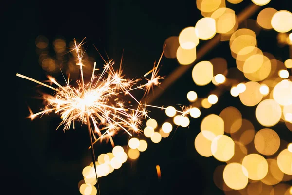 Sparklers on blurred christmas lights. Festive mood — Stock Photo, Image