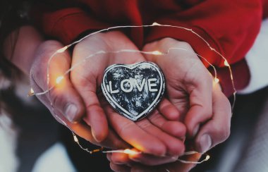 Taştan kalbi aşk metniyle tutan eller. Bulanık arkaplan