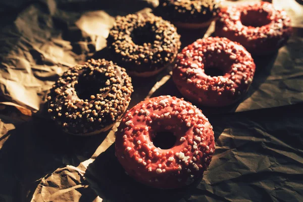 Fresh chocolate and raspberry donuts on crumpled craft paper — Stock Photo, Image