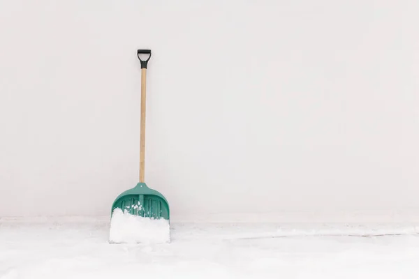 Pala de nieve apoyada contra la pared blanca de la casa —  Fotos de Stock