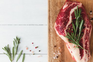 Güvertede çiğ biftek, biber, biberiye ve pembe Himalaya tuzu.