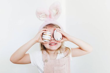 Paskalya yumurtası ve tavşan kulaklı küçük kız.