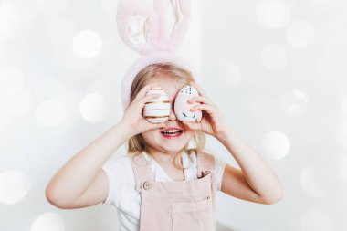 Paskalya yumurtası ve tavşan kulaklı küçük kız.