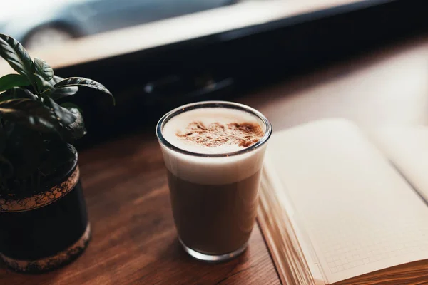 Una taza de café, un cuaderno en la mesa de la cafetería. Fondo borroso — Foto de Stock