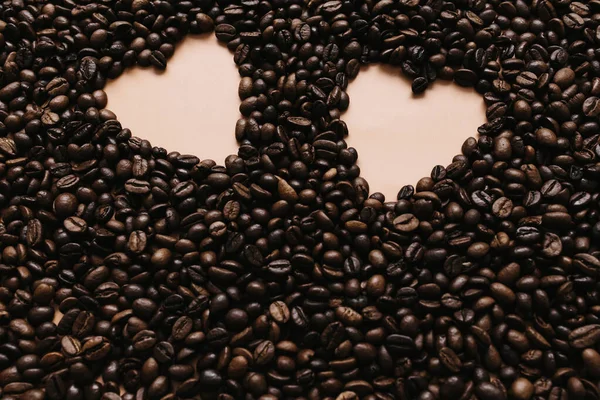 Arrière-plan avec une gamme de grains de café secs avec deux formes de coeur. Beige — Photo