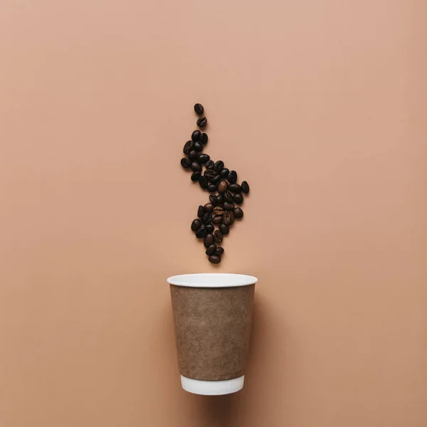 Fondo beige con taza de café de papel, granos de café vapor de café caliente — Foto de Stock