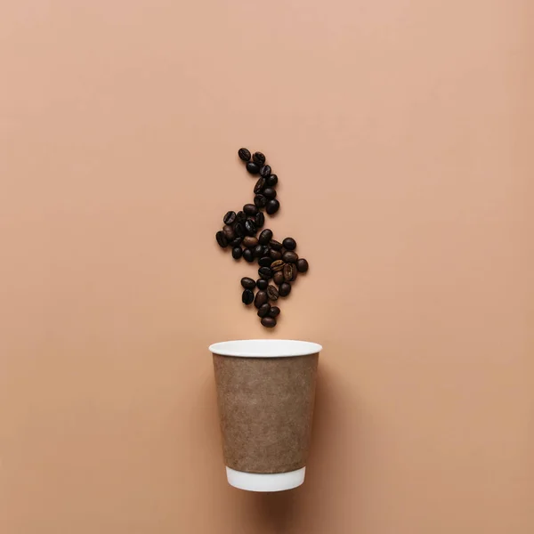 Beżowe tło z papierową filiżanką kawy, parą ziaren kawy z gorącej kawy — Zdjęcie stockowe