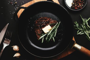 Dökme demir tavada pirzola, biberiye, sarımsak, çatal, tereyağı
