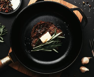 Dökme demir tavada pirzola, biberiye, sarımsak, çatal, tereyağı