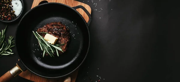 stock image Cooked ribeye steak, cast-iron pan, pepper, rosemary, salt, garlic, butter