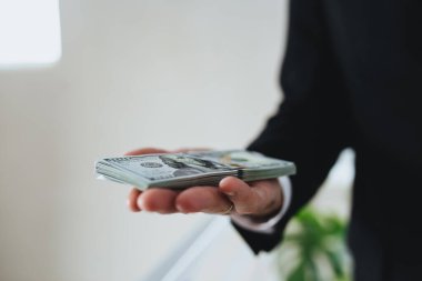 100 dolarlık banknotlar, takım elbiseli ve beyaz gömlekli bir adamın elinde. Arka plan bulanık. Yüksek kalite fotoğraf