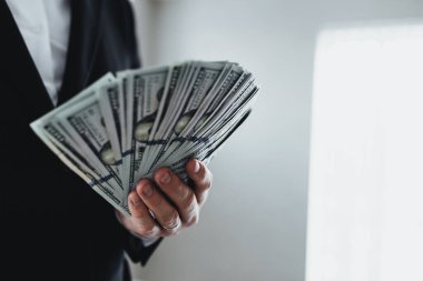 Yüz dolarlık banknotlar. Para eğlencesi. Takım elbiseli ve beyaz gömlekli bir adamın elinde. Arka plan bulanık. Yüksek kalite fotoğraf