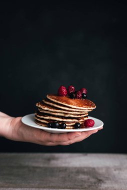 Böğürtlenli krep ve beyaz tabakta insan eli, ahşap masa. Yüksek kalite fotoğraf
