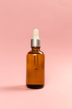 Pembe arka planda bir şişe kozmetik yağı. Yüksek kalite fotoğraf