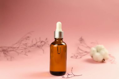 Pembe arka planda kurutulmuş bitkilerle birlikte bir şişe kozmetik yağı. Yüksek kalite fotoğraf