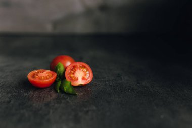 Gri arka planda yeşil fesleğenli kırmızı kiraz domatesleri. Yüksek kalite fotoğraf