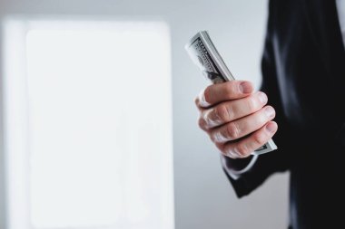 100 dolarlık banknotlar, takım elbiseli ve beyaz gömlekli bir adamın elinde. Arka plan bulanık. Yüksek kalite fotoğraf