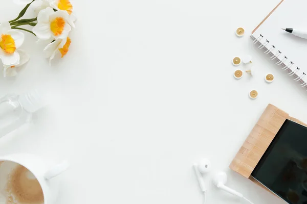 Office work, education flat lay concept with clips, phone, earphones, cup of coffee, pencil and notepad, and tulip flowers on white background. High quality photo