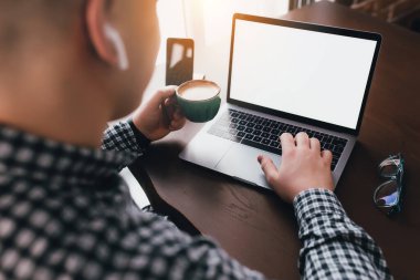 Laptopta bir fincan kahve ve kulaklıkla çalışan bir adam. Arka plan bulanık. Yüksek kalite fotoğraf