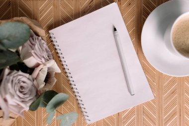 Romantik bir sabah. Yatağında çiçekler olan ahşap sehpa. Kahve fincanı, çiçekler, not defteri, kalem. Okaliptüs ve şakayıklı leylak gülleri. Yüksek kalite fotoğraf