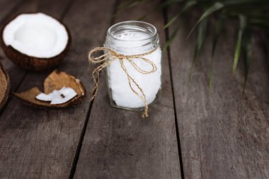 Gri ahşap arka planda hindistan cevizleri ve çiğ organik ekstra hindistan cevizi yağı ve palmiye yaprağı. Beyaz hindistan cevizi hamuru. Yüksek kalite fotoğraf