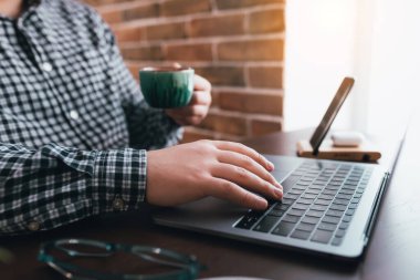 Evde bir fincan kahveyle dizüstü bilgisayarda çalışan bir adam. Arka plan bulanık. Yüksek kalite fotoğraf