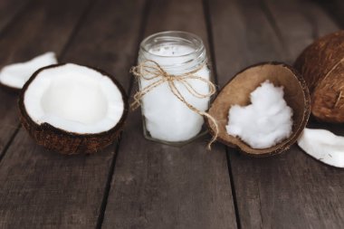 Gri ahşap arka planda kırılmış hindistan cevizi ve çiğ organik ekstra hindistan cevizi yağı. Beyaz hindistan cevizi hamuru. Yüksek kalite fotoğraf