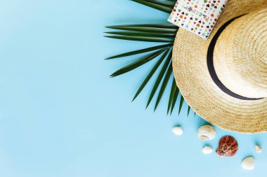 Seyahat, tatil konsepti. Deniz kabuklu şapka, yaprak, mavi arka planda pasaport.
