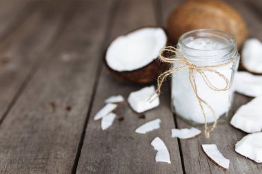 Gri ahşap arka planda kırılmış hindistan cevizi ve çiğ organik ekstra hindistan cevizi yağı. Beyaz hindistan cevizi hamuru. Yüksek kalite fotoğraf