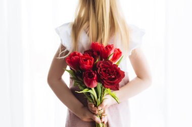 Küçük kız elinde bir buket kırmızı lale çiçeği tutuyor. Paskalya için tebrik kartı konsepti, Anneler Günü, Uluslararası Kadınlar Günü, Sevgililer Günü. Yüksek kalite fotoğraf